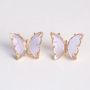 Macro shot of purple glass butterfly earrings with gold frame and crystal accents