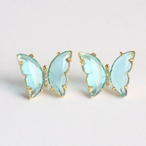 Close-up of mint green glass butterfly earrings with gold edges and zircon details