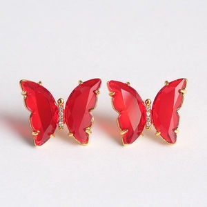 Macro shot of red butterfly earrings with golden prongs and central white zircon