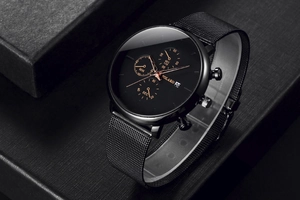Detail of a men's quartz watch featuring a black mesh strap and rose gold chronograph dials.