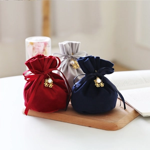 Velvet drawstring wedding favor bags in red, grey, and navy with golden charms