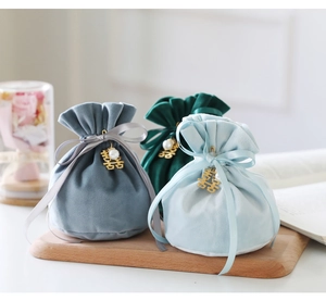 Close-up of velvet wedding favor bags in blue and green with golden pendants and pearls