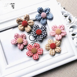 Close-up of seven assorted checkered fabric flowers for DIY accessories and crafts