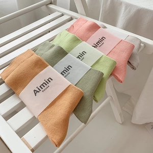 Set of Morandi color cotton crew socks in orange, green, and pink on wooden shelf