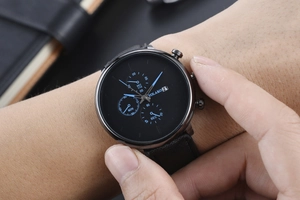 Close-up of men's quartz watch with black leather strap and chronograph sub-dials on wrist