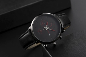 Detail of black quartz watch face with chronograph dials, date window, and leather strap