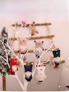 Close-up of plush Christmas gnome ornaments with star hats hanging on white branches