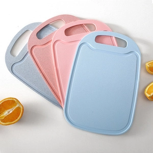 Detail view of wheat straw cutting boards in pastel colors with fresh orange slices