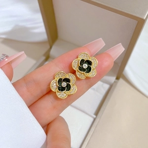 Close-up of camellia stud earring in gold and black enamel with sparkling crystals