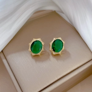 Detailed close-up of emerald green oval earrings with gold plating and zircon halo