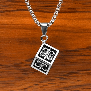 Punk style silver cube pendant necklace with fleur-de-lis pattern on wooden background