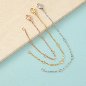 Detailed view of adjustable jewelry extenders with lobster clasps in gold, silver, and rose gold