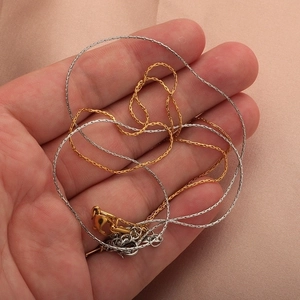 Close-up of gold and silver snake chain necklaces held in hand with lobster clasps