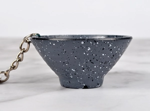 Macro view of a creative grey mini bowl keychain with unique paint splatter and metal chain