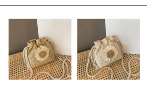 Detail of woven straw bucket bag featuring a white daisy flower and drawstring closure