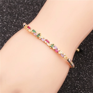 Golden bracelet with multi-colored baguette stones and beads on a model's wrist