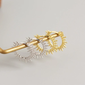 Close-up of S925 sterling silver hoop earrings with sunburst design in gold and silver