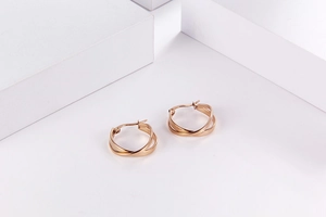 Dettaglio di orecchini a cerchio in acciaio al titanio oro rosa con design a doppio strato