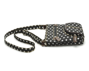 Detail of black canvas crossbody bag with white star pattern and brown leather trim