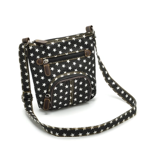 Detail of black canvas crossbody bag with white star pattern and brown leather accents