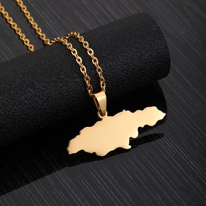 Detailed close-up of a gold Jamaica map pendant necklace on a dark textured surface