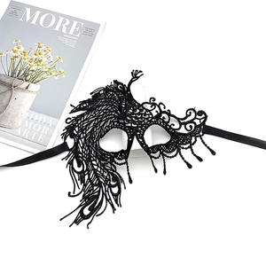 Detail of black lace party mask with peacock feather pattern and decorative tassels