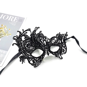 Flat lay of a black lace masquerade mask with silk ribbons next to a fashion magazine