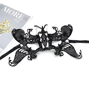 Detail of a black lace butterfly mask with satin ribbons on a minimalist white backdrop