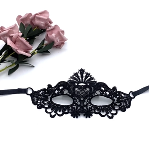 Detailed close-up of a black lace masquerade mask with intricate patterns and silk ribbons