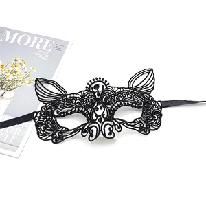 Close-up of intricate black lace masquerade mask with floral cutouts on a white background
