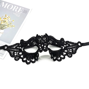 Flat lay of an intricate black lace masquerade eye mask with ribbon ties and floral texture