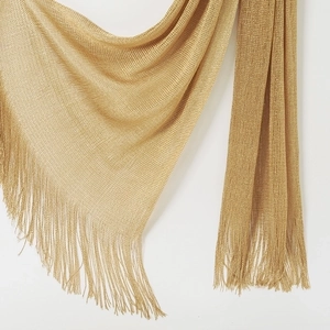 Detailed macro view of metallic gold woven texture and fringe trim on swimsuit cover up