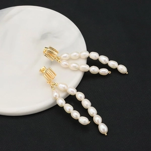 Detailed view of elegant gold brushed long tassel earrings with natural white freshwater pearls