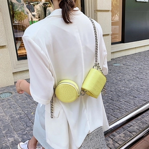 Neon yellow croco-patterned composite bag with silver chain strap worn over white blazer