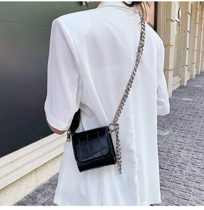Close-up of black crocodile pattern crossbody bag with a thick silver chain strap detail
