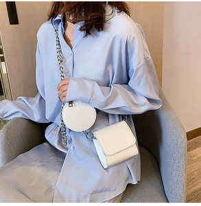 Close-up of white crocodile pattern crossbody bag with silver chain and coin purse detail