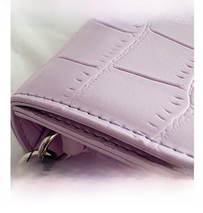 Detailed view of light purple crocodile pattern texture and silver hardware on shoulder bag