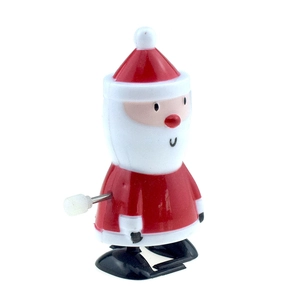 Macro view of a red wind-up Santa Claus toy with a side knob and walking base mechanism