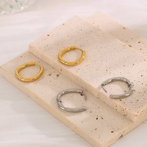 Macro view of gold and silver oval hinged hoop earrings on a stone textured background