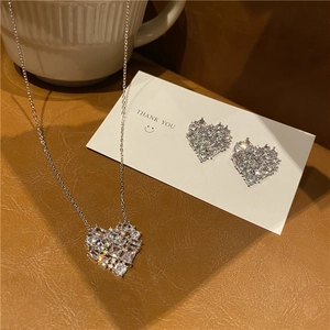 Close-up of sparkling heart-shaped jewelry set with crystal stones on leather texture