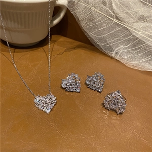 Close-up of heart-shaped jewelry set with necklace, earrings and ring on brown leather