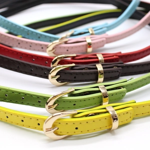 Close-up of colorful faux leather belts with golden horseshoe buckles for women
