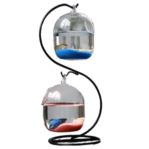 Hanging glass fish tank with black metal stand and two bowls filled with colorful sand