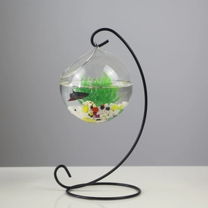 Hanging clear glass fish bowl with black metal stand and colorful sand base