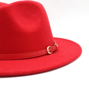Detailed close-up of red wool felt fedora featuring a slim band and golden crescent buckle
