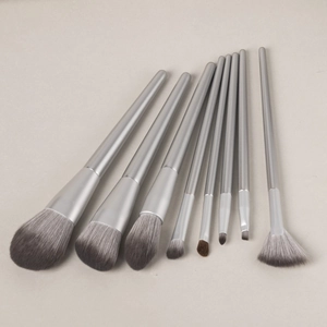 Detailed flat lay of 9 professional makeup brushes with silver handles and taupe bristles