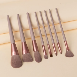 Detailed set of nine matte violet makeup brushes with rose gold ferrules on beige paper
