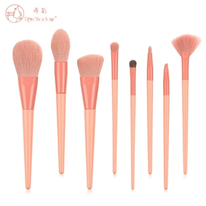 Detail view of 8 professional makeup brushes with coral orange handles and pink bristles