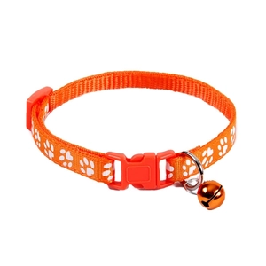 Detail of orange nylon pet collar with paw prints, safety buckle, and metal bell
