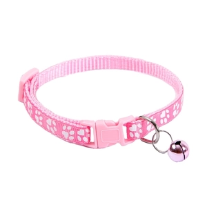Detail of pink pet collar featuring white paw prints, safety buckle and a shiny bell